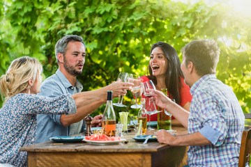 Group of friends toasting during a party on a terrace in summer