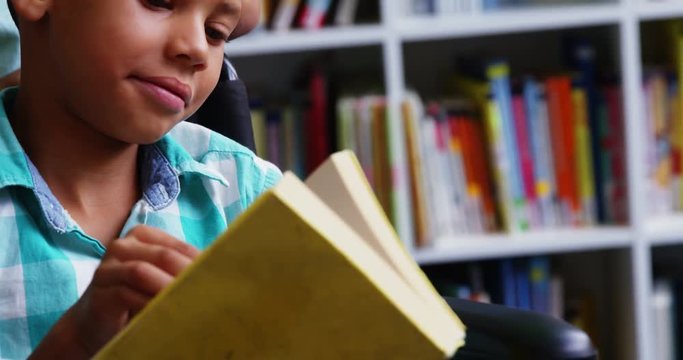Slow motion of disabled school boy reading book in library at school 4k