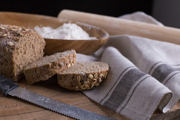 Fototapeta na wymiar Whole grain bread put on kitchen napkin decorated with almond with a chef holding dough roller at the background.