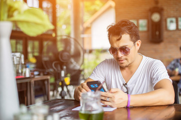 Businessman hands using cell phone with laptop at office desk.