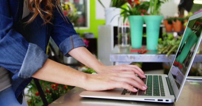 Beautiful female florist using laptop in flower shop