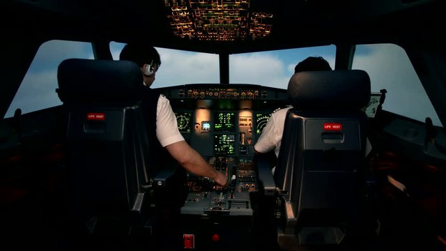 Front shot from the cabin of modern passenger aircraft. Plane is approaching storm, overcast or clouds. Probably there will be turbulence. Cockpit with cabin crew. Shot at training center