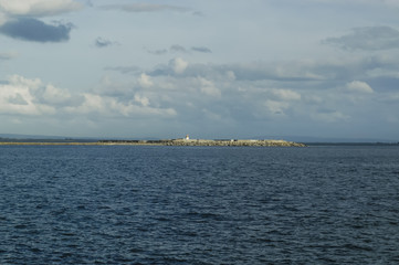 Island wih lighthouse in sea.