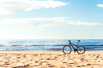 Fototapeta premium One bicycle standing on the beach sand on blue seascape backgrou