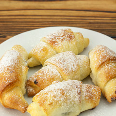 Homemade fresh bagels in white plate on wooden background.