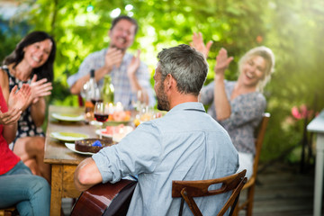 Summertime, man playing guitar for his friends on a terrace