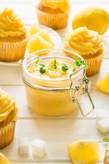 Preparing lemon cupcakes with citrus curd on white wooden background. Selective focus