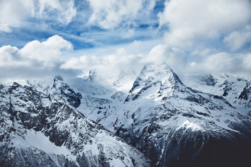 Obraz premium Dramatic panorama of snowy high mountains below cloudy sky in winter time Wild nature picture