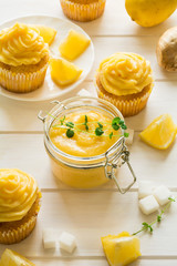 Preparing lemon cupcakes with citrus curd on white wooden background. Selective focus