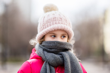 Closeup portrait of cute baby girl wearing knitted hat and winter jacket outdoors