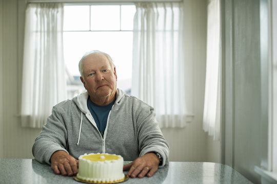Portrait of a senior man sitting in front of a birthday cake.