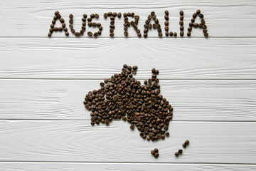 Map of the Australia made of roasted coffee beans laying on white wooden textured background. Space for text