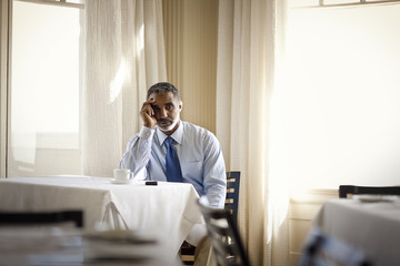 Worried businessman sitting on his own in restaurant.