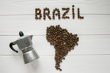 Map of the Brazil made of roasted coffee beans laying on white wooden textured background with coffee maker. Space for text