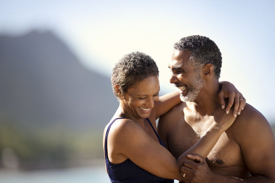 Mid adult couple standing with their arms around each other on a beach.