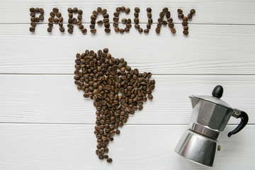 Map of the Paraguay made of roasted coffee beans laying on white wooden textured background with coffee maker. Space for text