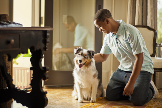 Smiling teenage boy petting a dog.