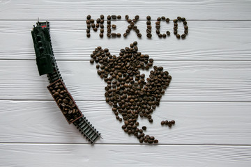 Map of the Mexico made of roasted coffee beans laying on white wooden textured background with toy train