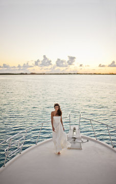 Portrait of a bride standing on the prow of a boat.