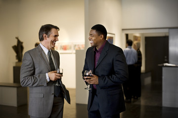 Business colleagues attend an art gallery opening.