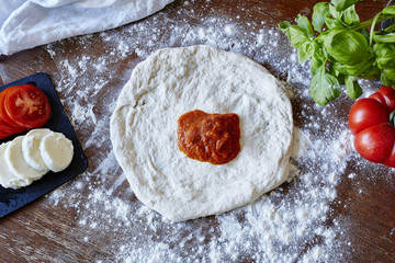 baking pizza rolled out dough with splash of sauce
