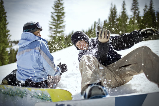 Happy couple having fun with their snowboards outdoors in the snow.
