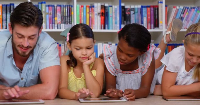 School kids and teacher using digital tablet in library at school 4k