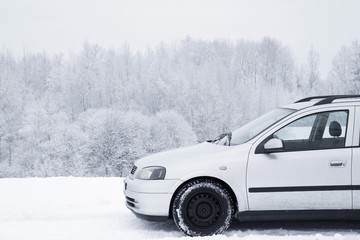 Car driving or parking on white snowy countryside road in nice winter day. Tree branches are snow covered and look very beautiful. 