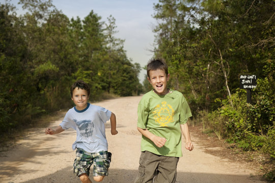 Portrait of two smiling brothers running on the dirt road