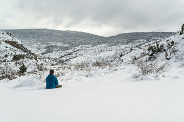 Hombre joven sentado frente a un paisaje nevado