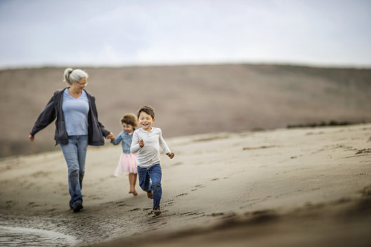 Fototapeta Grandmother walking on the beach with her grandchildren