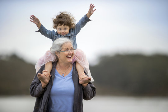 Mature woman carrying her granddaughter on her shoulders.