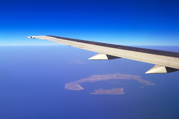 Aerial view of airplane wing and volcanic Santorini island in Greece