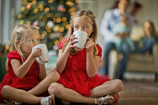 Two young girls drinking hot chocolates.