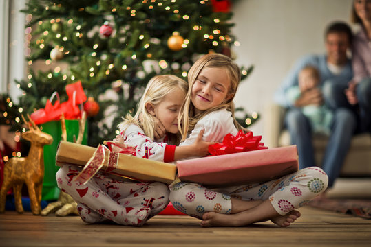 Two young girls hugging with their Christmas presents.