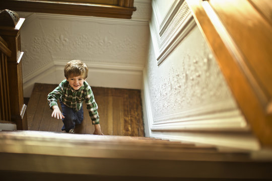 Young boy climbing up the staircase.