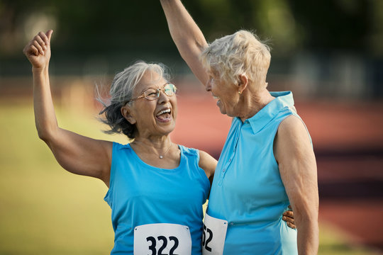 Two happy senior women laughing after competing in an athletic event.