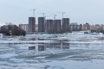 The reflection of the construction of five towers in the winter river