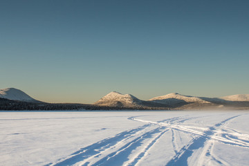 Pistes de motoneige sur lac gel&eacute; dans les montagnes du Yukon