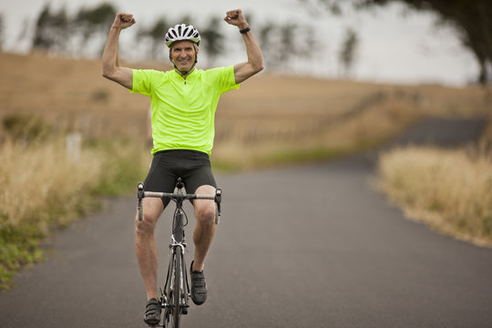 Portrait of a smiling mature man showing off on a bike.
