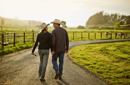 Happy mid adult couple smiling at one another while walking on a farm.
