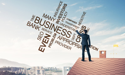 Young businessman standing on house roof and writing leadership 