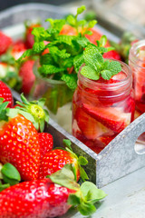 Homemade strawberry lemonade with mint on a dark wooden background