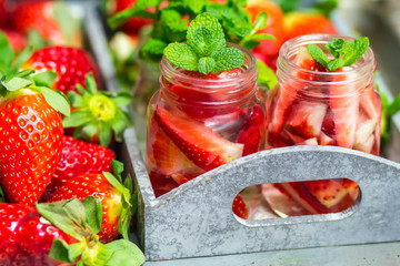 Homemade strawberry lemonade with mint on a dark wooden background