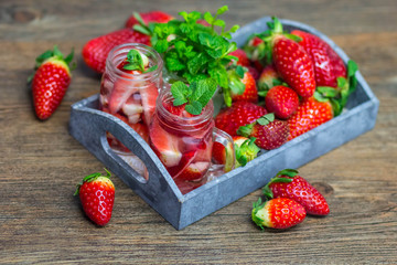 Homemade strawberry lemonade with mint on a dark wooden background
