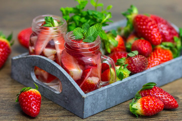 Homemade strawberry lemonade with mint on a dark wooden background