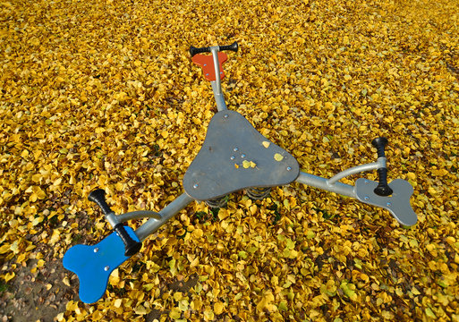 eine federwippe auf einem mit laub bedecktem kinderspielplatz