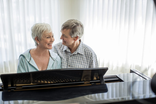 Affectionate mature couple enjoy playing the piano together.