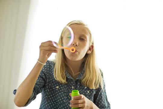 Happy teenage girl blowing bubbles.
