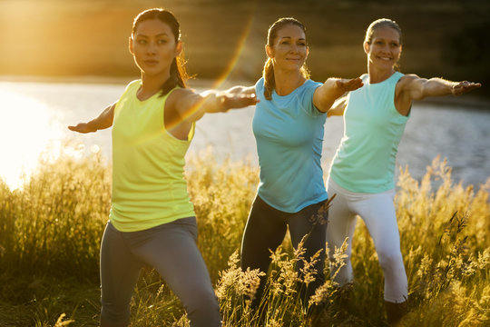 Female friends practicing yoga in a rural field
